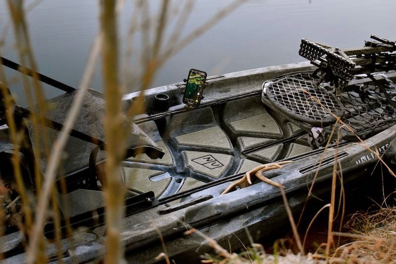 A camo NuCanoe rigged with gun racks, tucked into the reeds